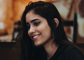 Young woman with winged eyeliner smiling while sitting at table