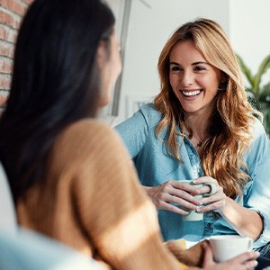 Two friends smiling while enjoying cup of coffee together