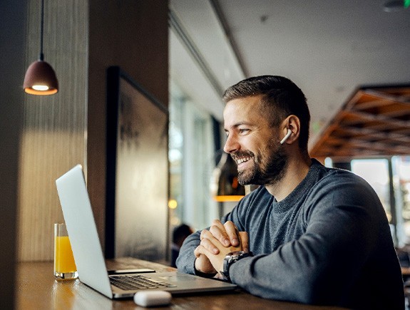 Man smiling while working on laptop in cafe