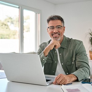 Man smiling while working on computer at home