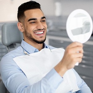 Patient smiling at reflection in handheld mirror
