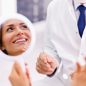 Woman smiling in reflection of handheld mirror