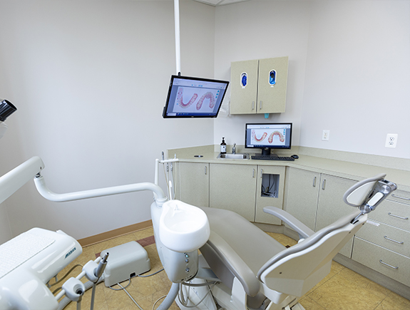 Dental treatment room with digital models of teeth on monitors