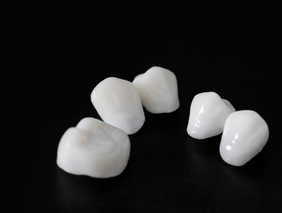Five dental crowns in front of a black background