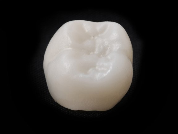Tooth colored dental crown against black background
