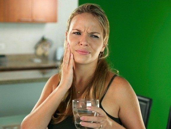 Blonde woman holding her cheek in pain