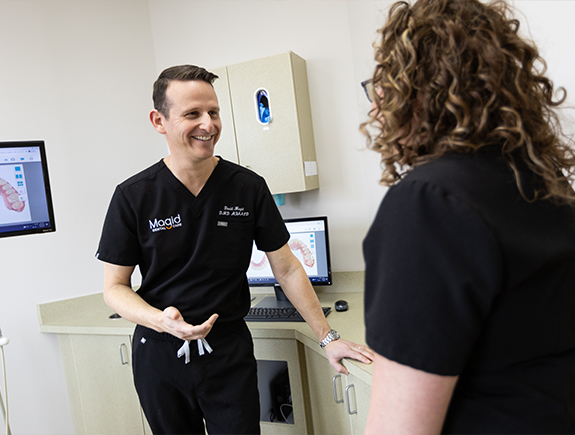 Doctor Magid smiling while talking to dental patient