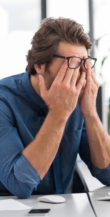 Man sitting at office desk and rubbing his eyes