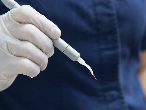 Gloved hand holding a dental soft tissue laser