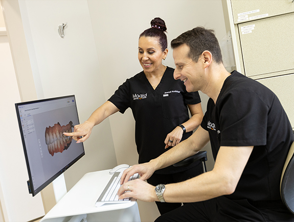 Doctor Magid and dental team member looking at digital models of teeth on computer