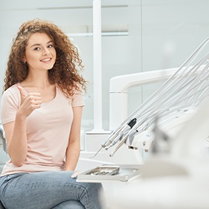 Female dental patient in pink shirt giving thumbs up