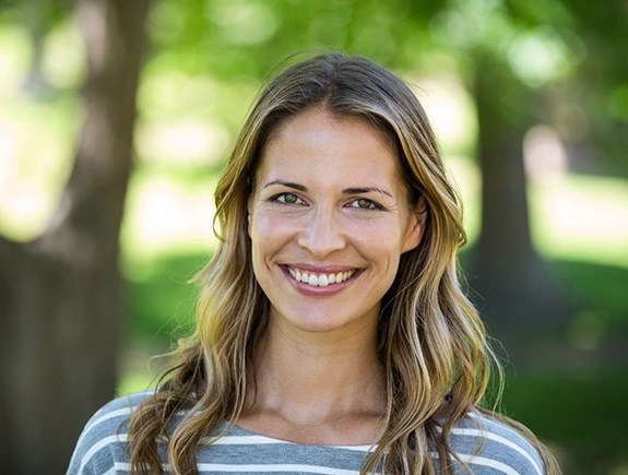 Woman standing outside smiling with a striped shirt