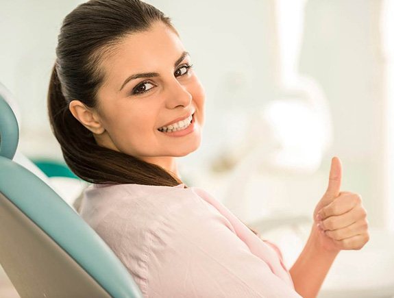 Woman in dental chair giving a thumbs-up