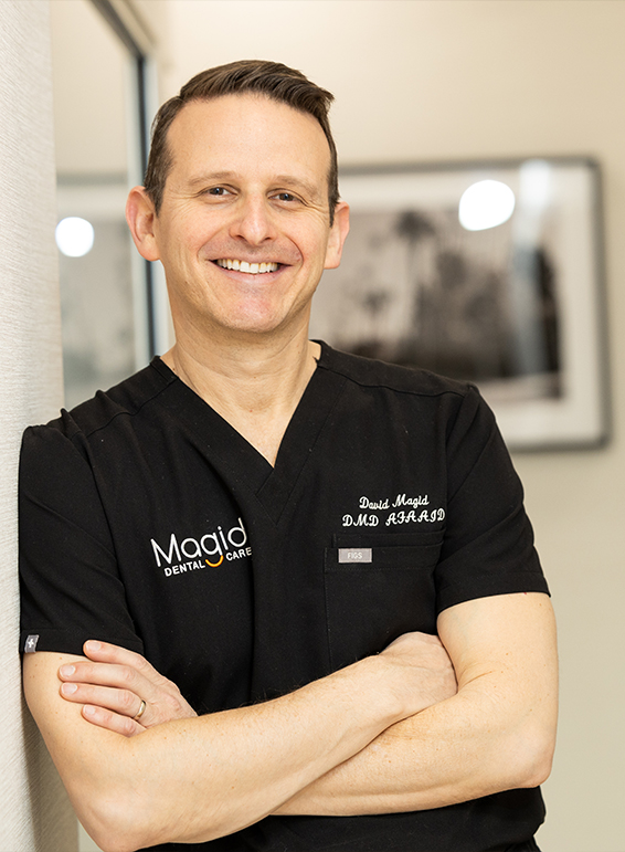 West Caldwell New Jersey dentist Doctor David Magid smiling and leaning against wall