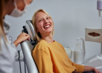Woman in yellow sweater smiling at her dentist