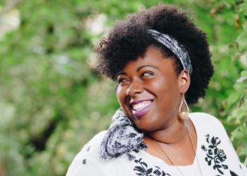 Woman in flowery black and white blouse grinning outdoors