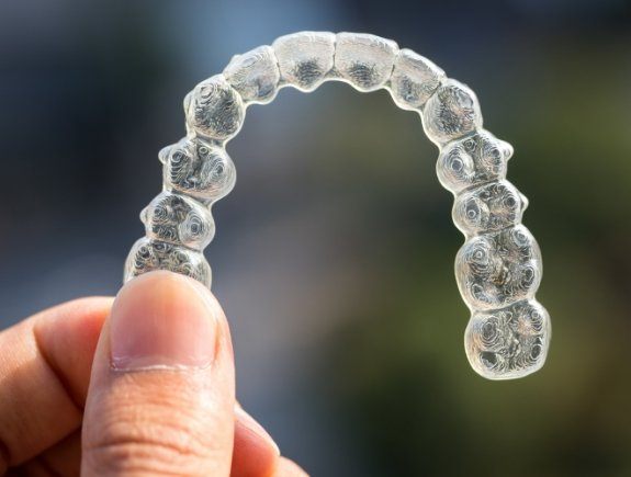 Person holding Invisalign aligner in West Caldwell in their hand
