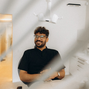 Patient with black glasses smiling in treatment chair