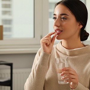 Woman holding a pill by her mouth