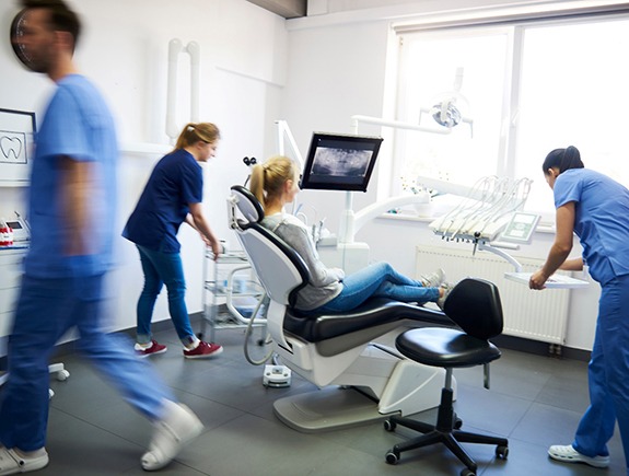 Dentist and assistants busy working around a patient looking at X-rays