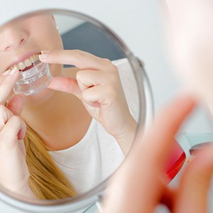 Girl in mirror inserting oral appliance