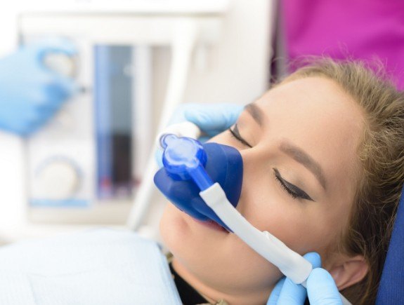 Young woman wearing nitrous oxide mask while visiting sedation dentist in West Caldwell