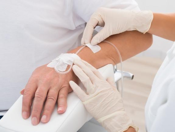 Medical professional placing an I V into the arm of a patient