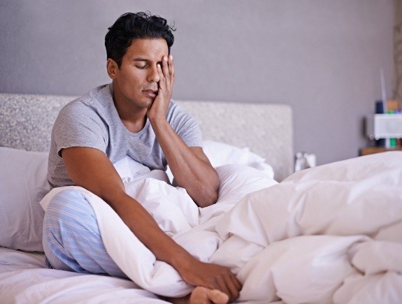 Man in bed resting his head in his hand