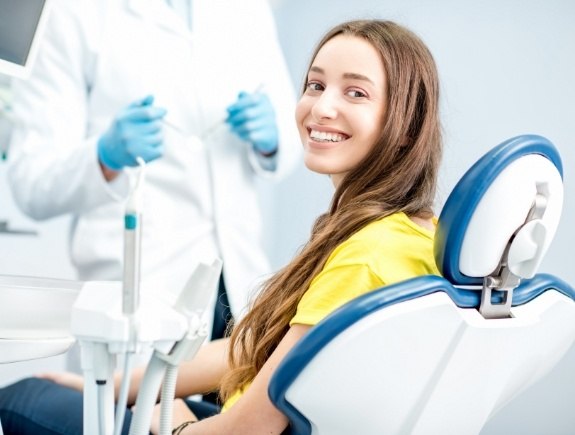 Young woman in yellow shirt smiling in dental chair