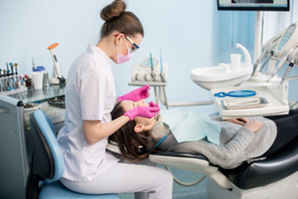 dental hygienist helping patient